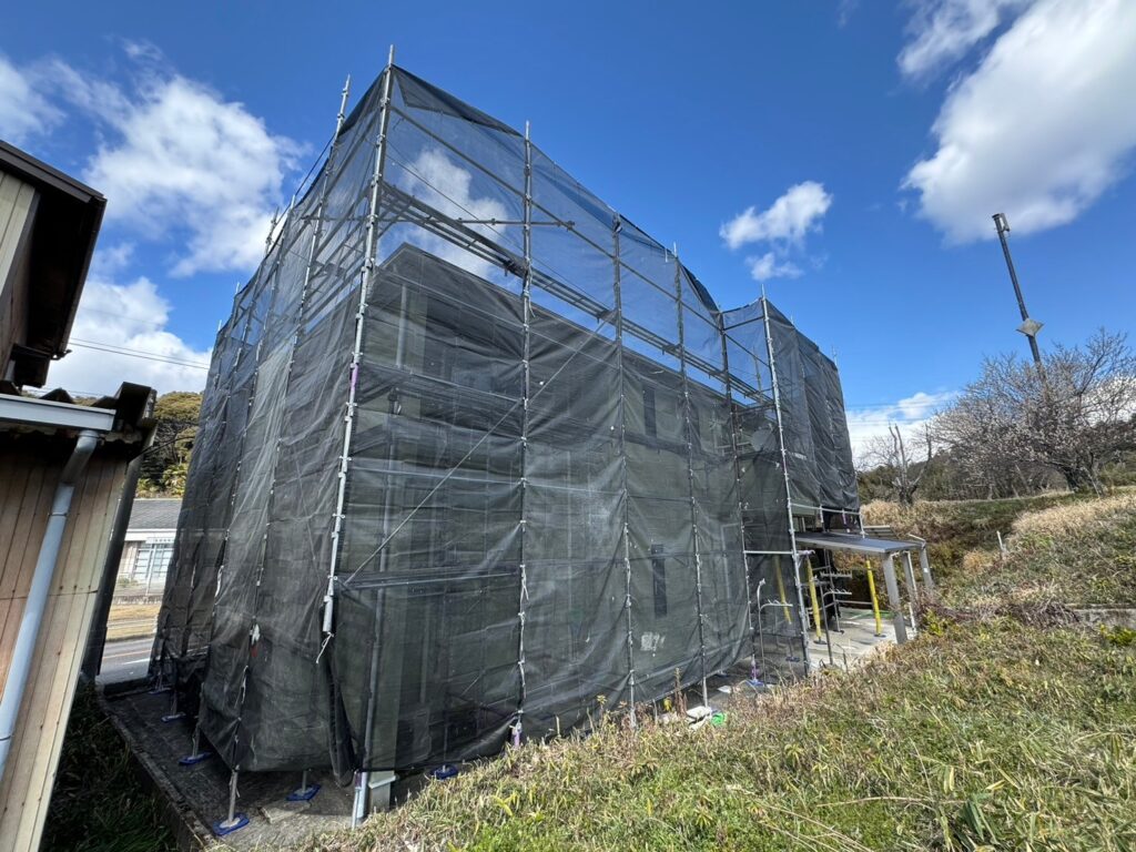 【足場設置・メッシュシート展開】<br />
職人が安全かつ精密な作業を行うための足場を組み立てました。近隣の皆様へ塗料や水が飛散するのを防ぐため、お家全体をしっかりとメッシュシートで囲い、配慮を徹底します。